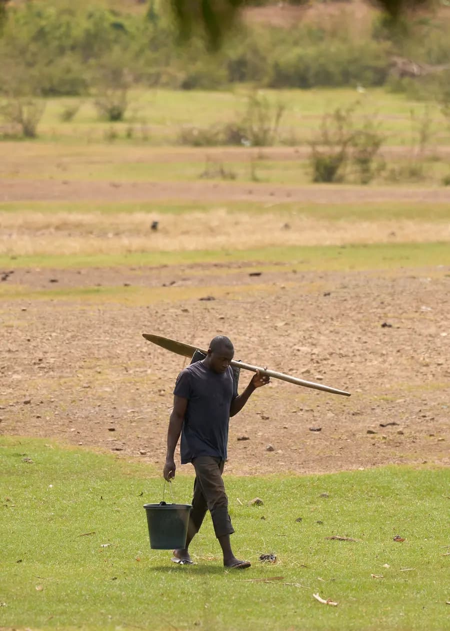 Illustration — agriculteur portant une houe dans un champ rural